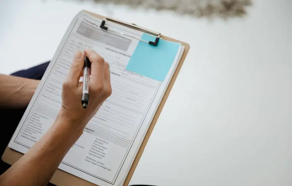 Personne remplissant un constat d'assurance après un sinistre, téléphone et documents sur la table